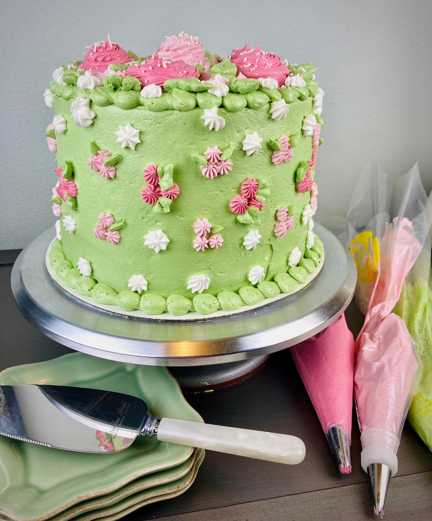 Tall, round spring green cake with pink and white flowers